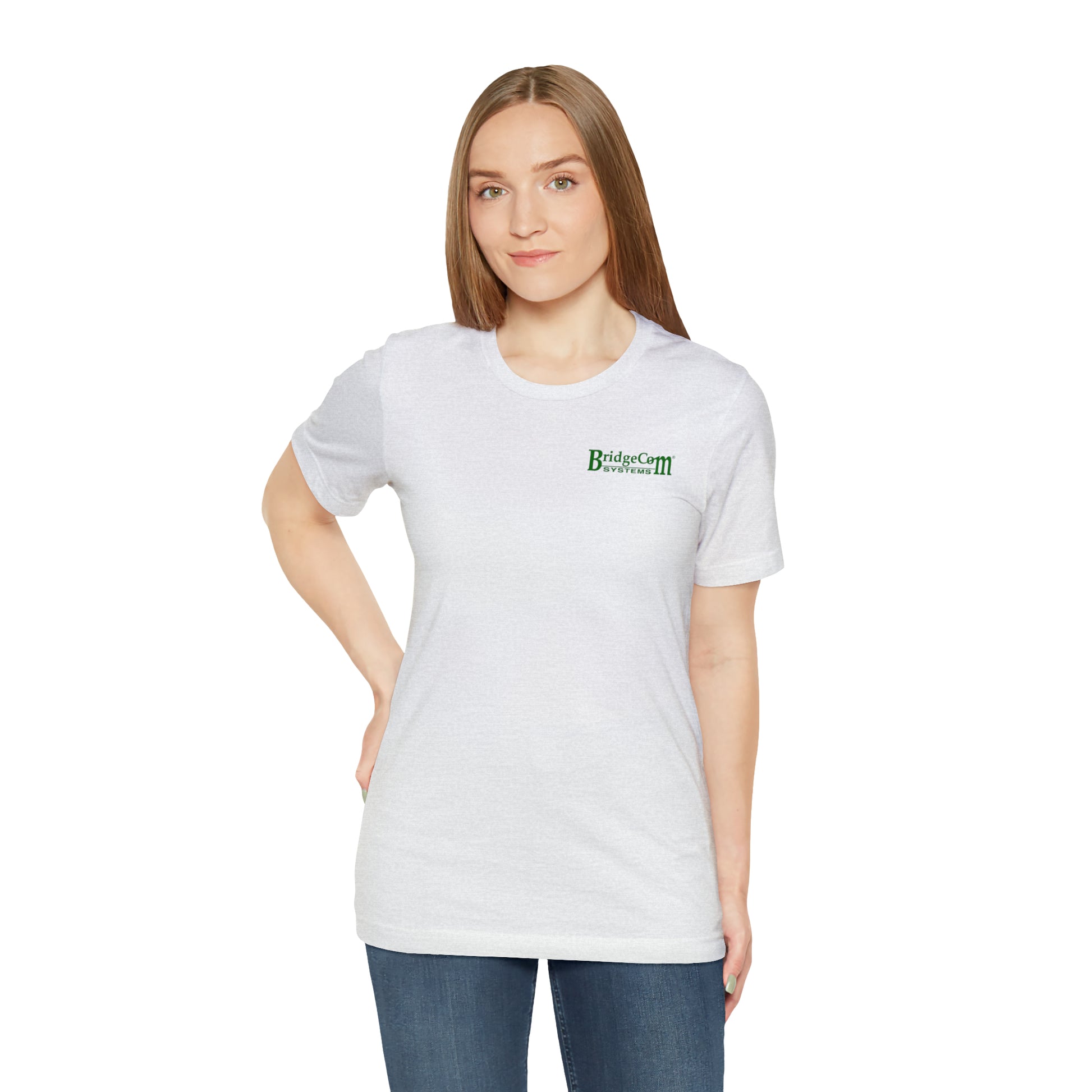 An individual with long straight hair is wearing a white Short Sleeve Tee - Small Logo shirt from BridgeCom Systems, which features a green logo on the left chest. Crafted from 100% Airlume combed and ringspun cotton, it boasts a retail fit. The person stands against a plain white background, with one hand on their hip and a neutral expression on their face.