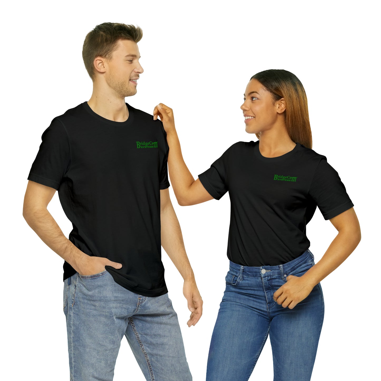 A man and a woman are standing side by side, smiling at each other. Both are wearing black Short Sleeve Tees with small green BridgeCom Systems logos and blue jeans. The woman has her right hand on the man's shoulder. The background is plain white.
