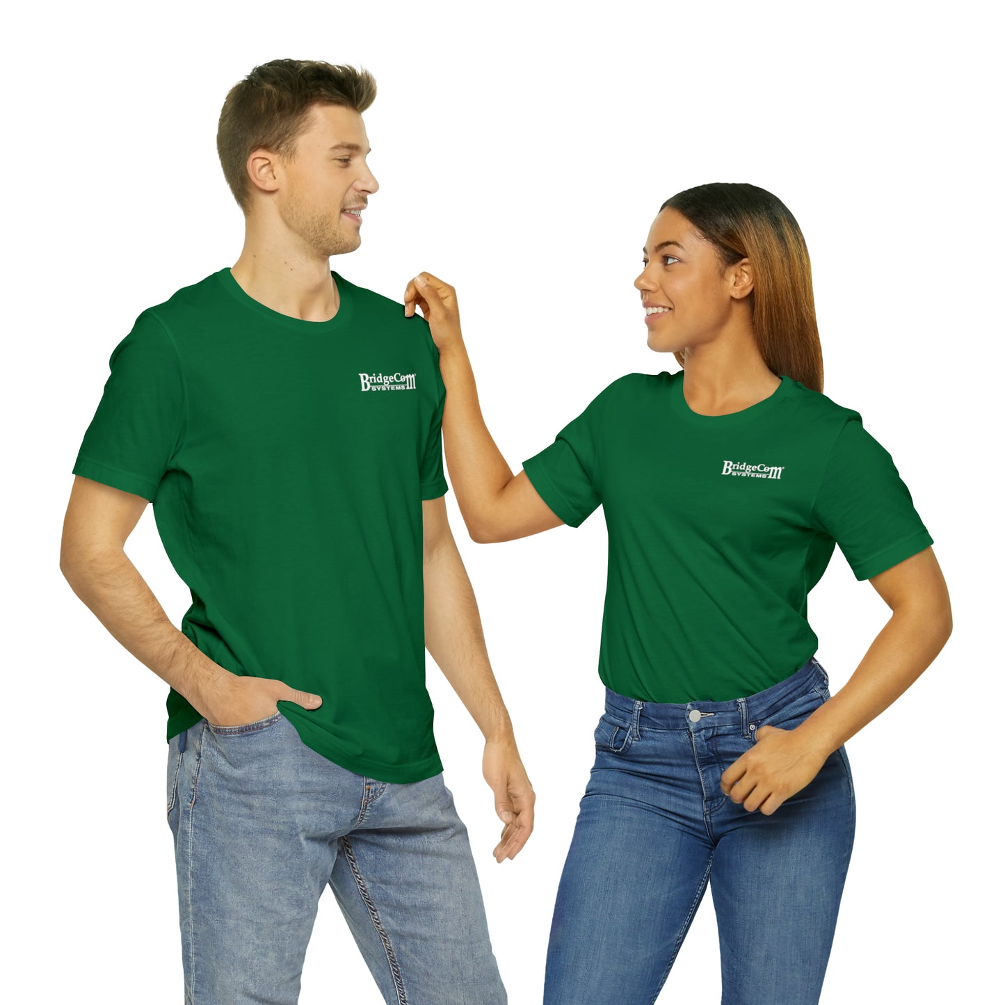 A man and a woman stand next to each other, both wearing the Short Sleeve Tee - Small Logo in green, featuring the "BridgeCom Systems" logo on the left chest. The woman touches the man's shoulder while they smile at each other. Both are also wearing jeans against a white background, showcasing seamless communication.