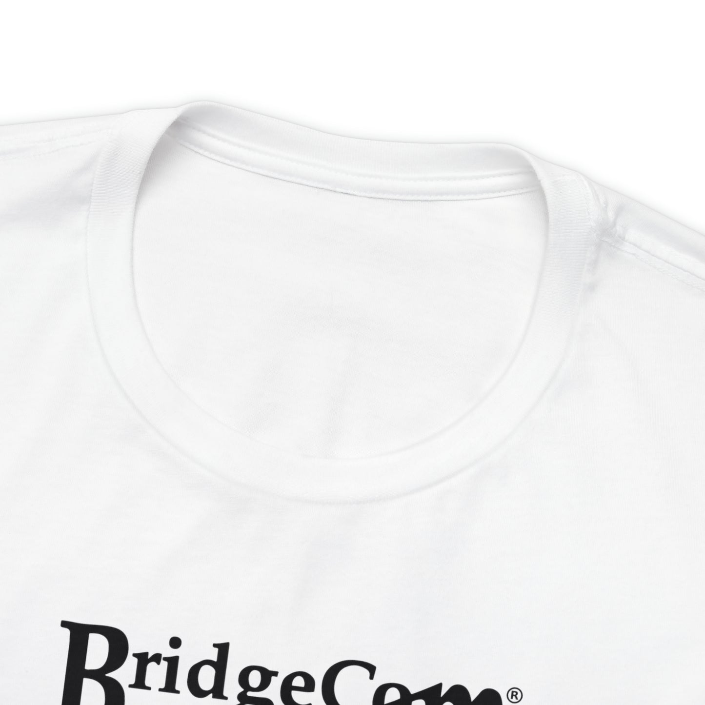 A close-up view of an Airlume cotton white Unisex Short Sleeve BridgeCom Tee - Alternate Logo with the top part and its collar visible. The text "BridgeCom" is partially visible in black letters near the bottom of the image, highlighting the fine texture and stitching of this communication-themed shirt.