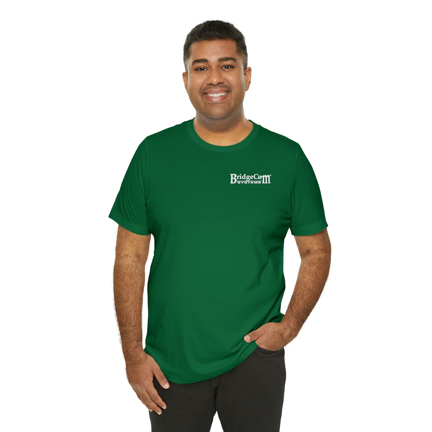 A person stands smiling, dressed in the Short Sleeve Tee - Small Logo made of Airlume combed cotton. The white "BridgeCom Systems" logo adorns the left chest. With their hands casually in their pockets against a plain white background, they epitomize seamless communication and comfort.