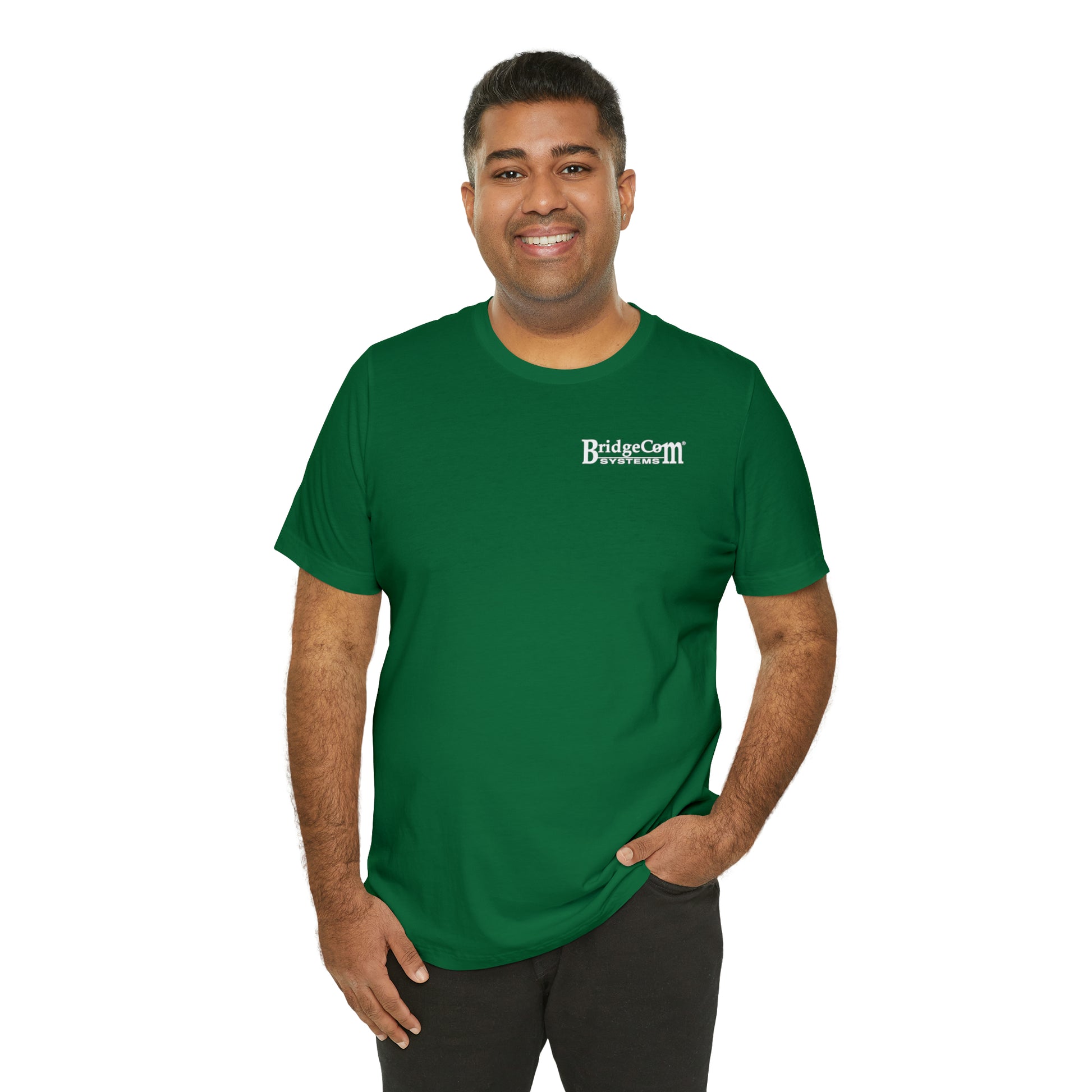 A person stands smiling, dressed in the Short Sleeve Tee - Small Logo made of Airlume combed cotton. The white "BridgeCom Systems" logo adorns the left chest. With their hands casually in their pockets against a plain white background, they epitomize seamless communication and comfort.