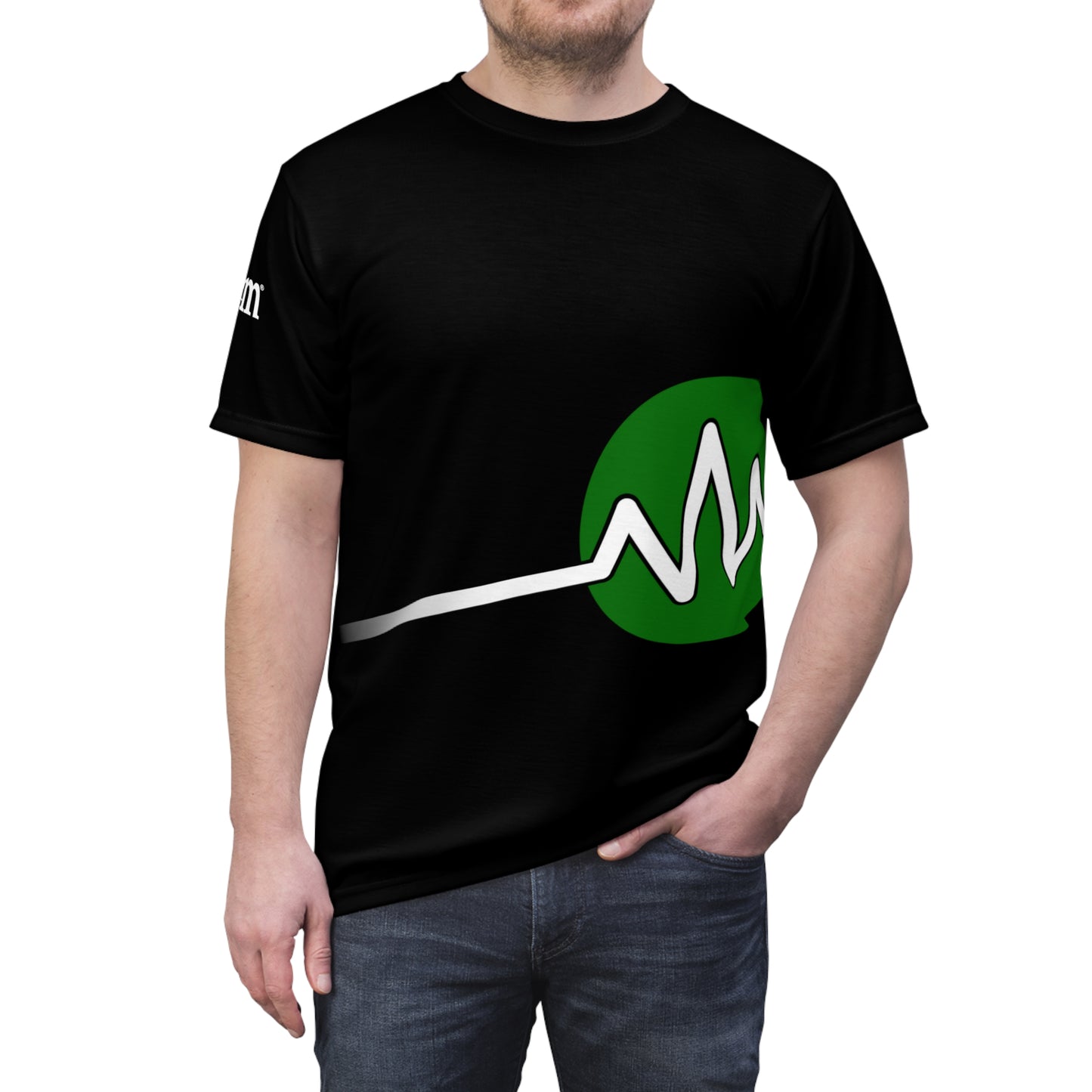 A person wearing the BridgeCom Unisex Tee - Alternate Logo, featuring a black t-shirt with a green circle and white line design that resembles a heartbeat wave pattern in the center. The distinctive logo on this tee adds a unique flair. With one hand in their pocket, they stand against a plain background, exuding casual confidence.