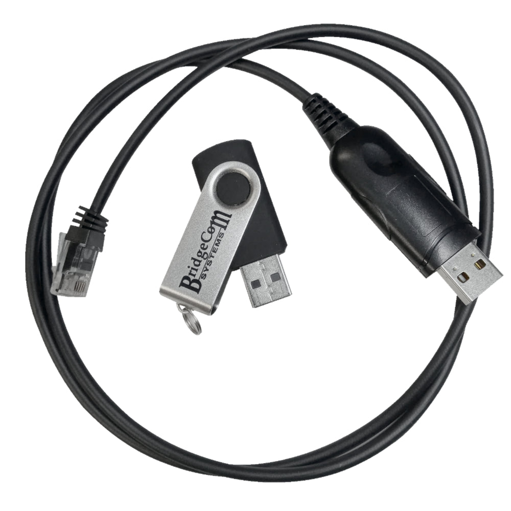 A coiled black USB cable with a standard USB male connector on one end and a square RJ45 connector on the other, accompanied by a silver USB flash drive with a rotating cover labeled "BridgeCom Systems," designed for use with BCM series mobile programming software, was laid on top of the cable.