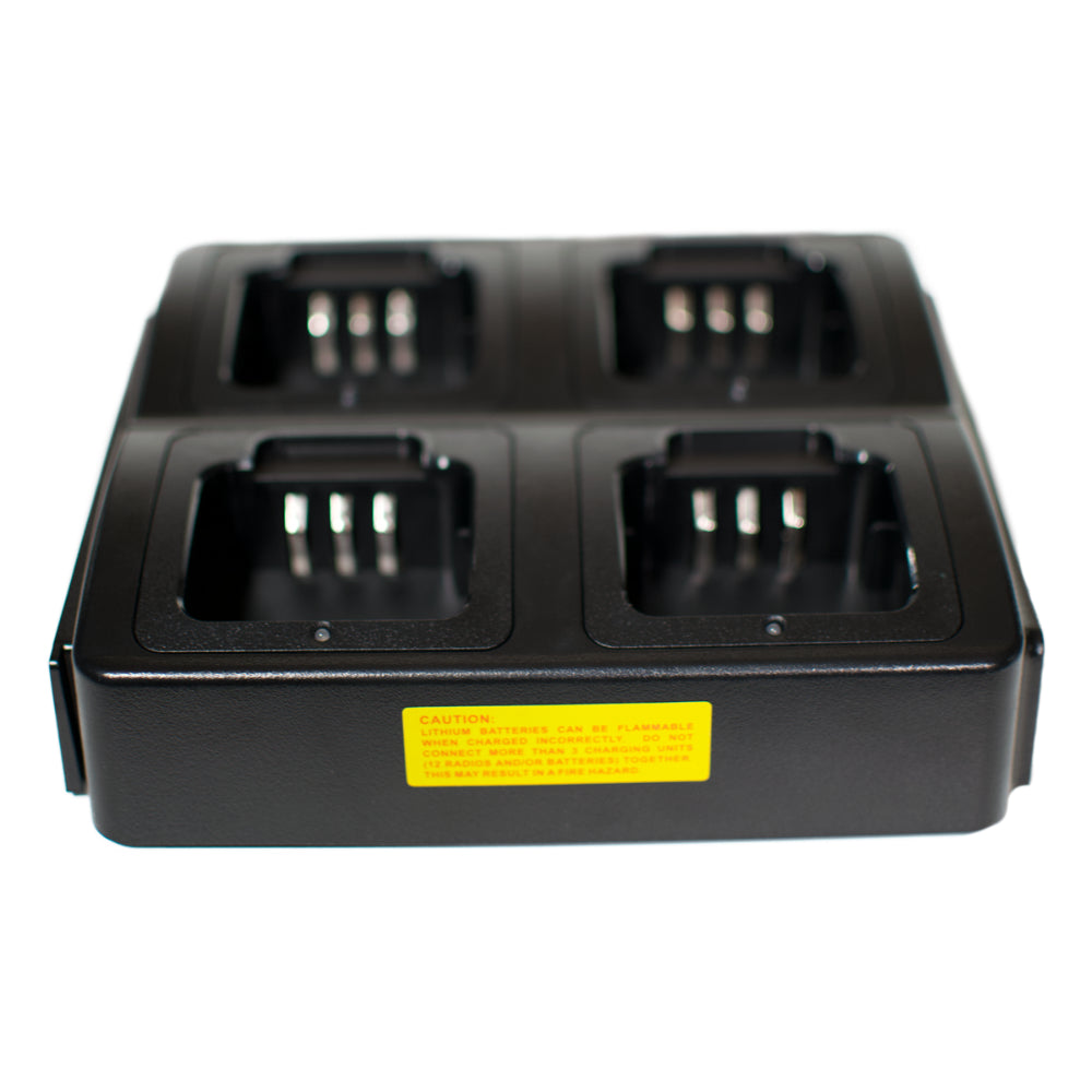 The Four Slot AnyTone 868/878 Rapid Gang Charger is a black, rectangular charging station designed with four individual slots for charging devices. Each slot features metal contacts at the bottom. The front of the charger prominently displays a yellow caution label with red text. This charger is perfect for an amateur radio club, capable of simultaneously charging four HTs from the AnyTone 868-878 series.