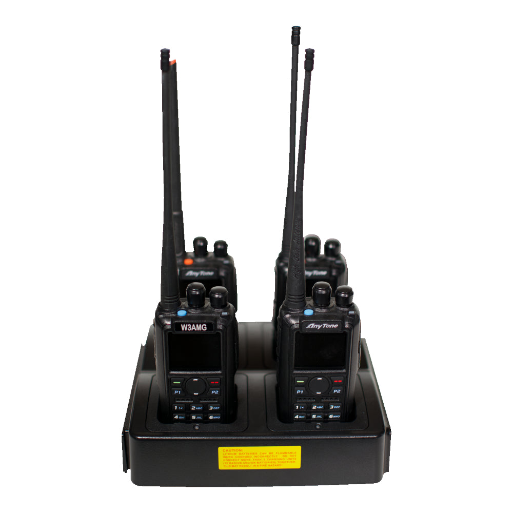 The Four Slot AnyTone 868/878 Rapid Gang Charger is displayed with four AnyTone 868-878 walkie-talkies, each featuring a long antenna. The walkie-talkies are neatly positioned in individual slots on the charger, which has a yellow label on the front. Perfect for any amateur radio club, these devices ensure you're always ready to communicate.