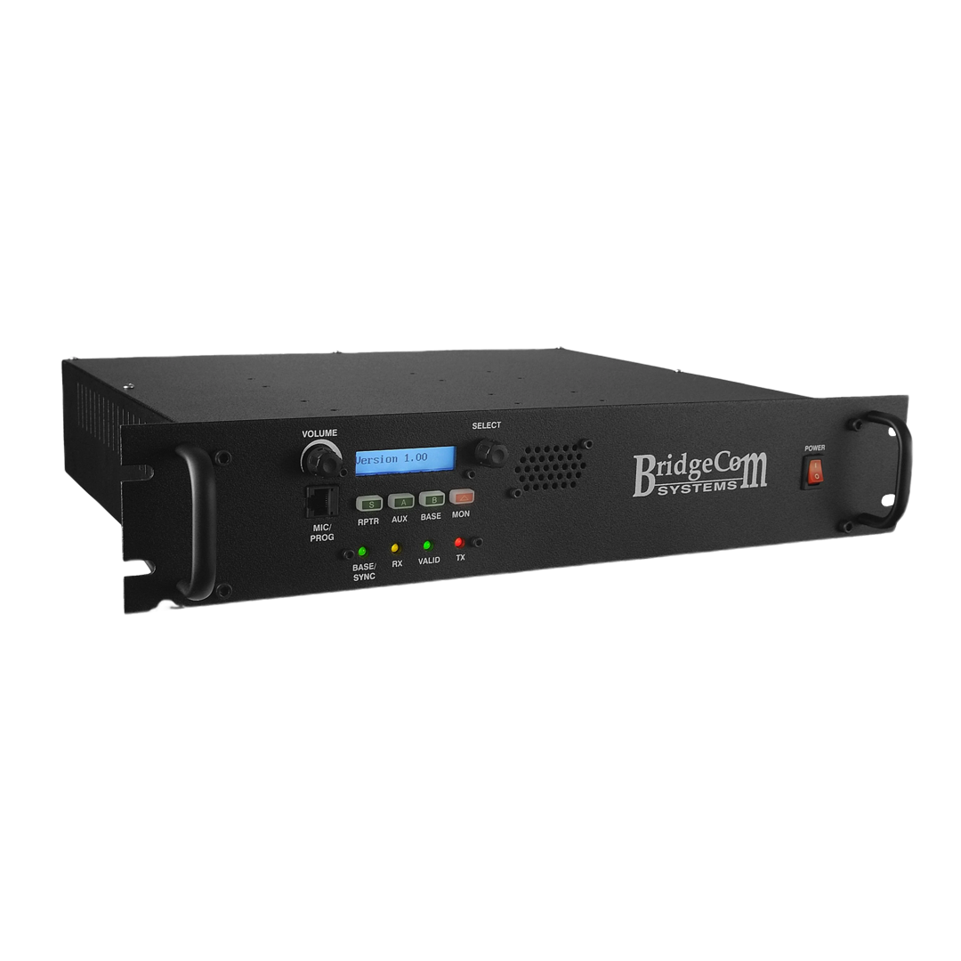 A black BridgeCom Systems radio repeater with control buttons, LCD display, and indicator lights, housed in a 19-inch rackmount case, viewed at an angle.