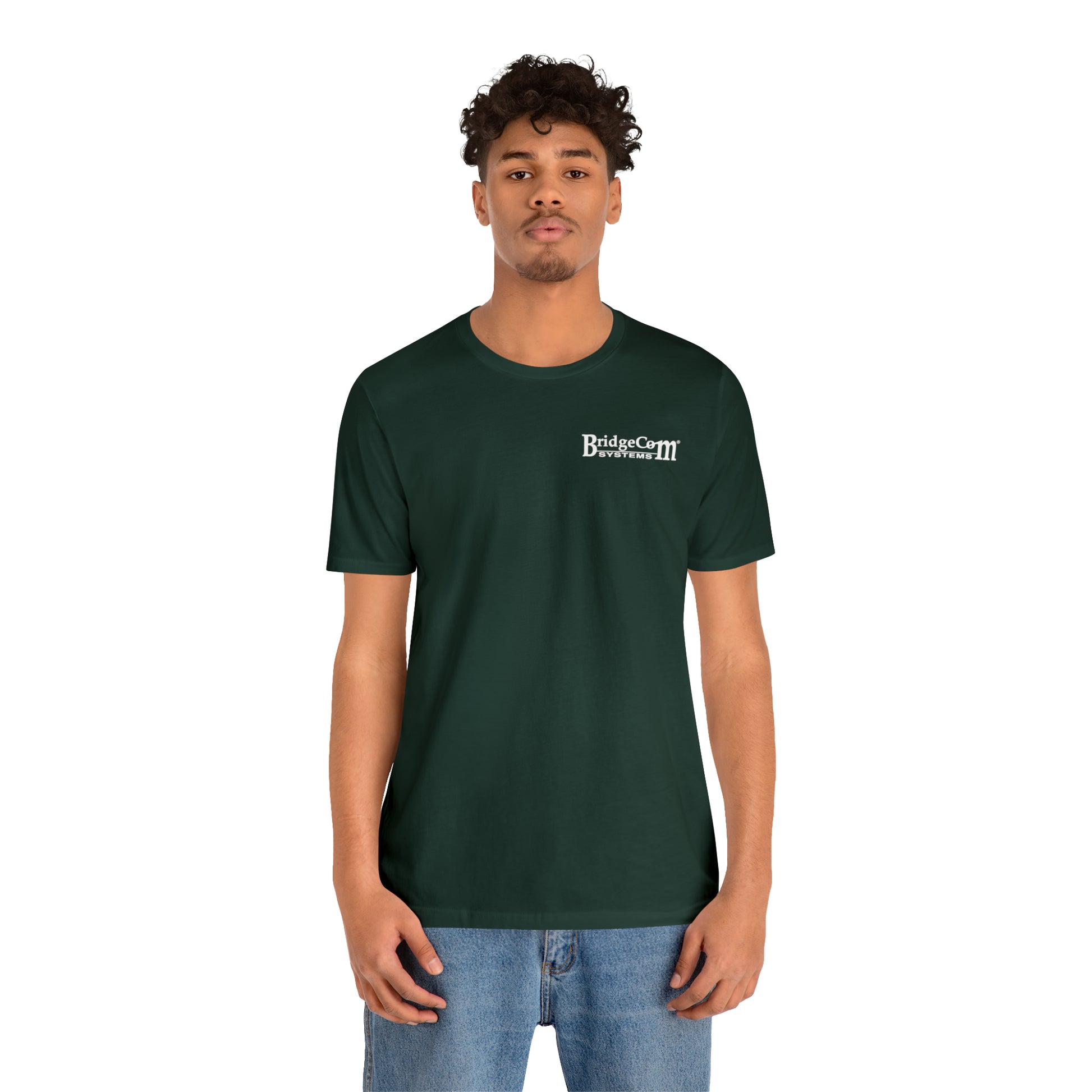 A person with curly hair is wearing a dark green Short Sleeve Tee - Small Logo and blue jeans. They are standing against a plain white background, facing the camera directly with a neutral expression.