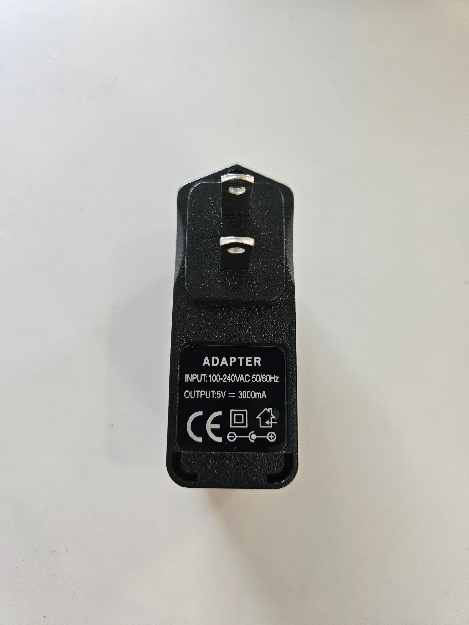 A black 5V 3A Skybridge Power Adapter - Wall Charger with two prongs and an informational label. The label details the input as 100-240V AC 50/60Hz and the output as 5V at 3000mA, along with various certification marks. The adapter is placed on a plain white background.