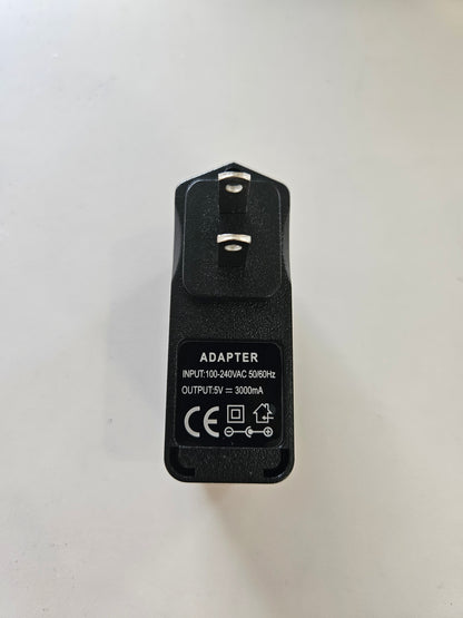 A black 5V 3A Skybridge Power Adapter - Wall Charger with two prongs and an informational label. The label details the input as 100-240V AC 50/60Hz and the output as 5V at 3000mA, along with various certification marks. The adapter is placed on a plain white background.