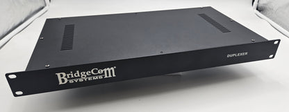 A black BCR-GMRS Repeater & Duplexer Power Bundle from BridgeCom Systems sits on a white surface. The metal unit features front mounting ears, side vents, and white branding, making it ideal for GMRS repeater setups.