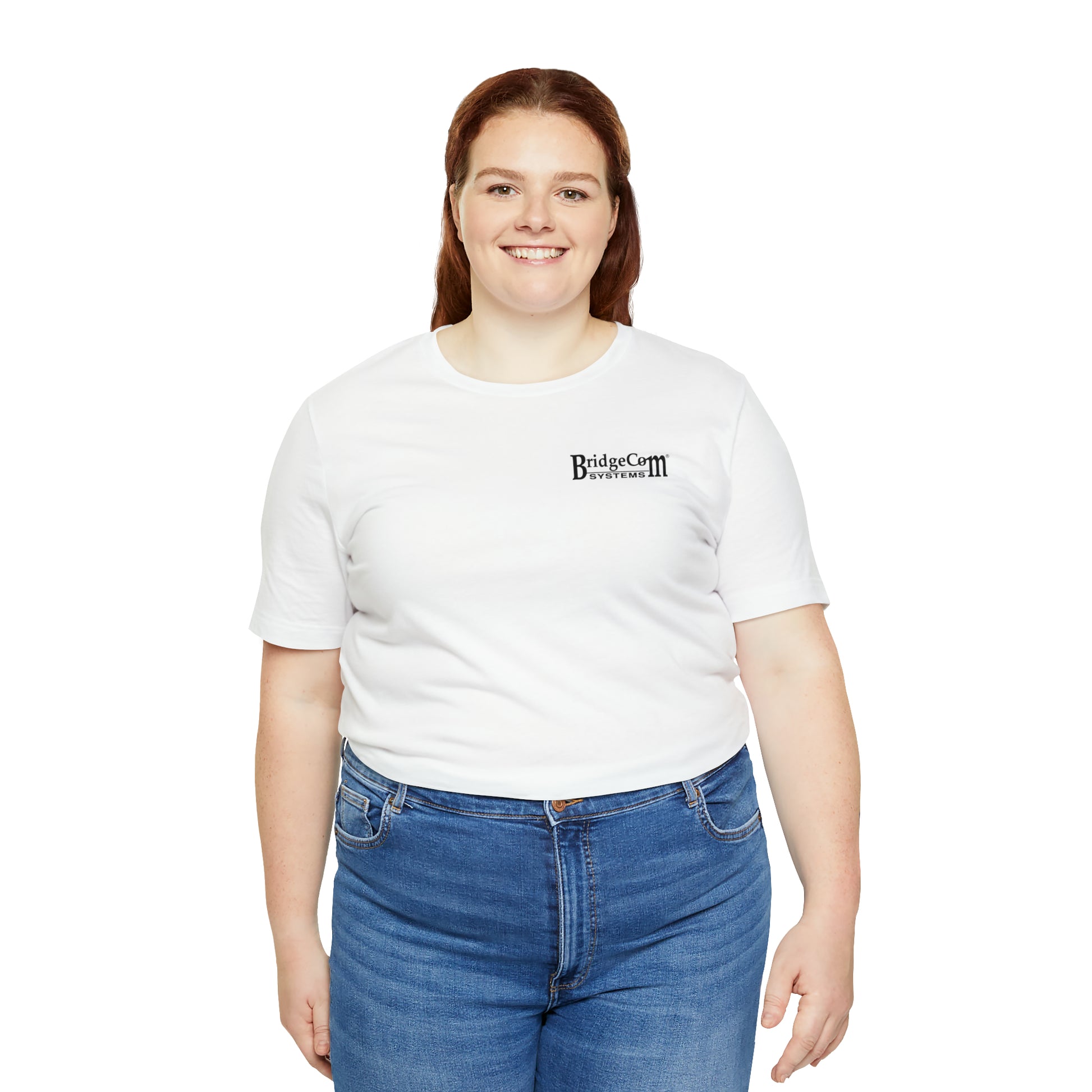 A smiling person with long red hair stands against a white background. They are wearing a Short Sleeve Tee - Small Logo proudly displaying "BridgeCom Systems," along with blue jeans, embodying the spirit of efficient communication.