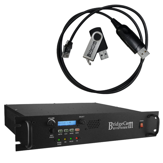 Displayed is the BCR-220 (220 MHz) Repeater MMDVM Digital package with a Programming Kit from BridgeCom Systems. The black, rack-mountable unit includes an array of buttons, an LCD screen, and indicator lights on its front panel, making it perfect for amateur ham radio enthusiasts. Positioned above it are a black USB cable and a USB flash drive featuring the BridgeCom logo.