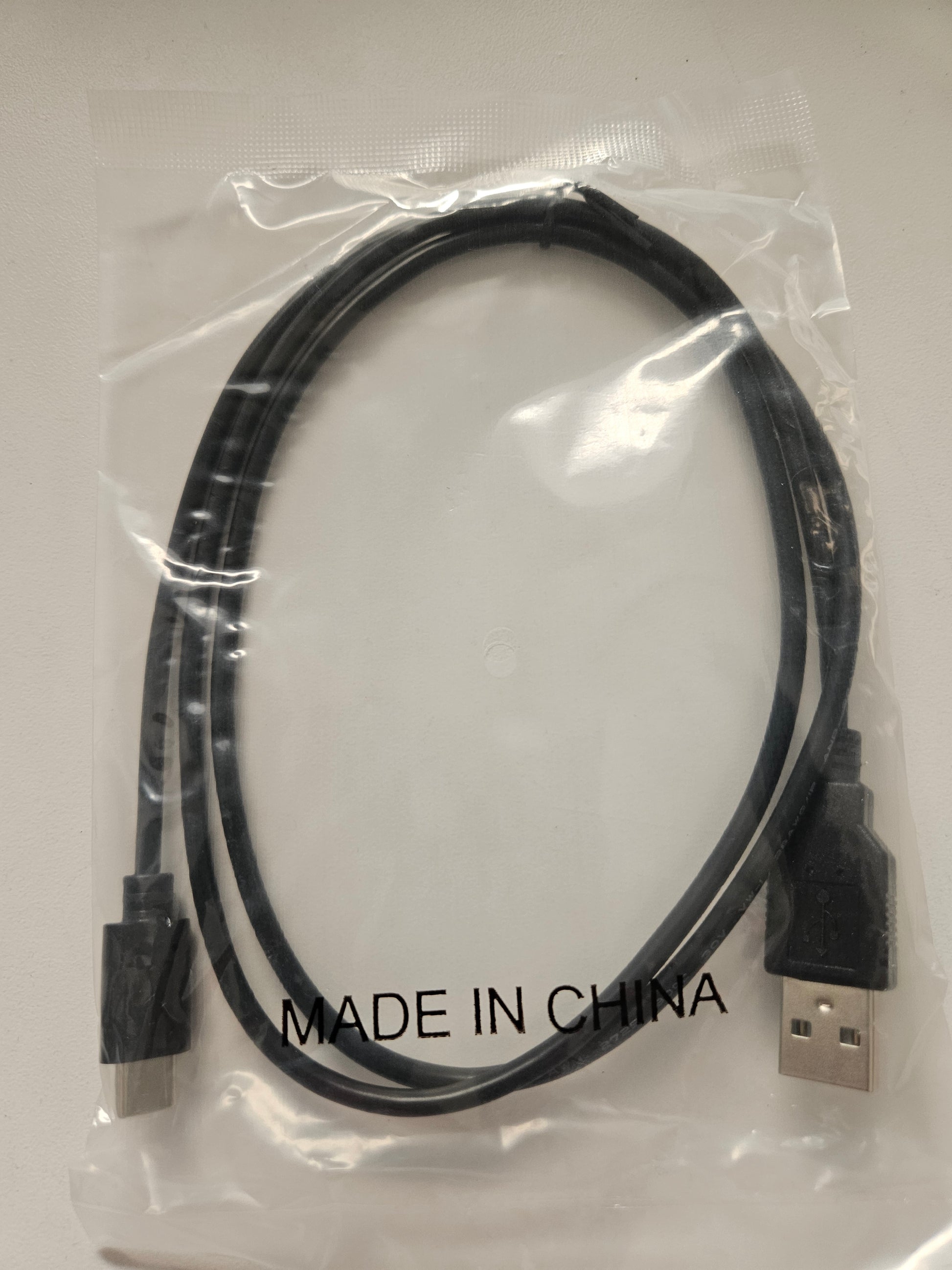 A USB Type A to USB Type C cable in black is packaged in a clear plastic bag labeled "MADE IN CHINA" and placed on a white surface.
