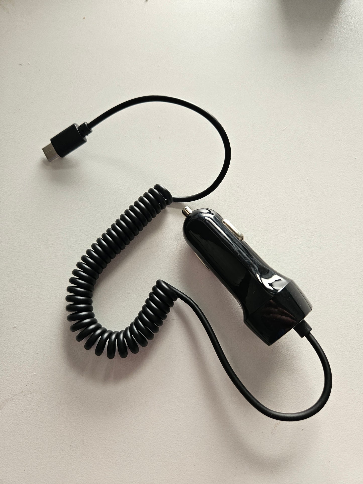 A Skybridge Car Power Adaptor car charger (12-24V input, 5V 3A output) with a USB-C connector is lying on a white surface.