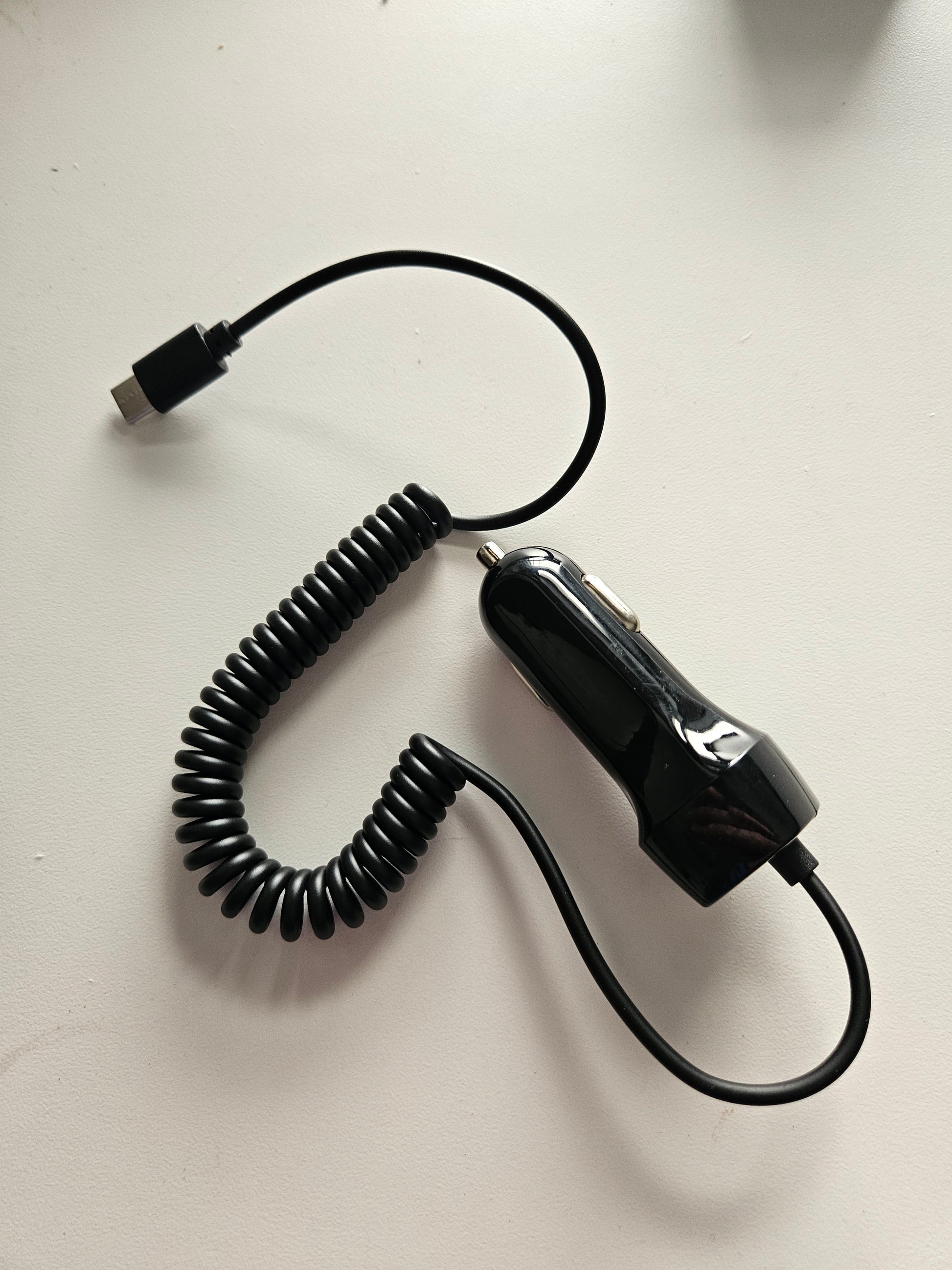 A Skybridge Car Power Adaptor car charger (12-24V input, 5V 3A output) with a USB-C connector is lying on a white surface.
