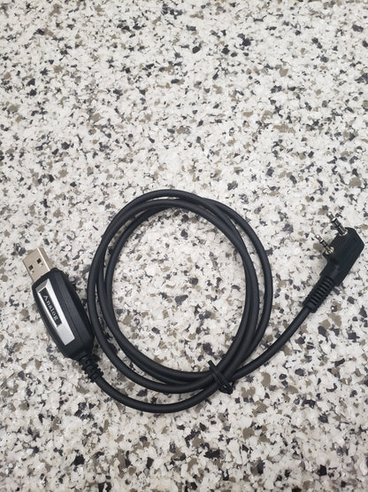 The BridgeCom Buddy Programming Cable, featuring a USB-A connector and a right-angle plug, rests coiled on a speckled surface—perfect for configuring your Buddy FRS handheld radio.