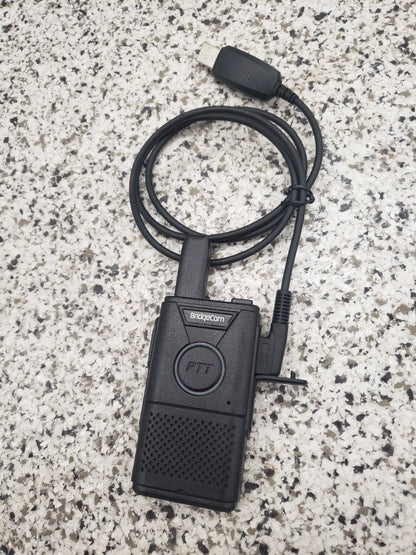 A black BridgeCom Buddy Programming Cable is coiled next to an FRS handheld radio on a speckled grey and white surface, ready for you to adjust your radio settings.